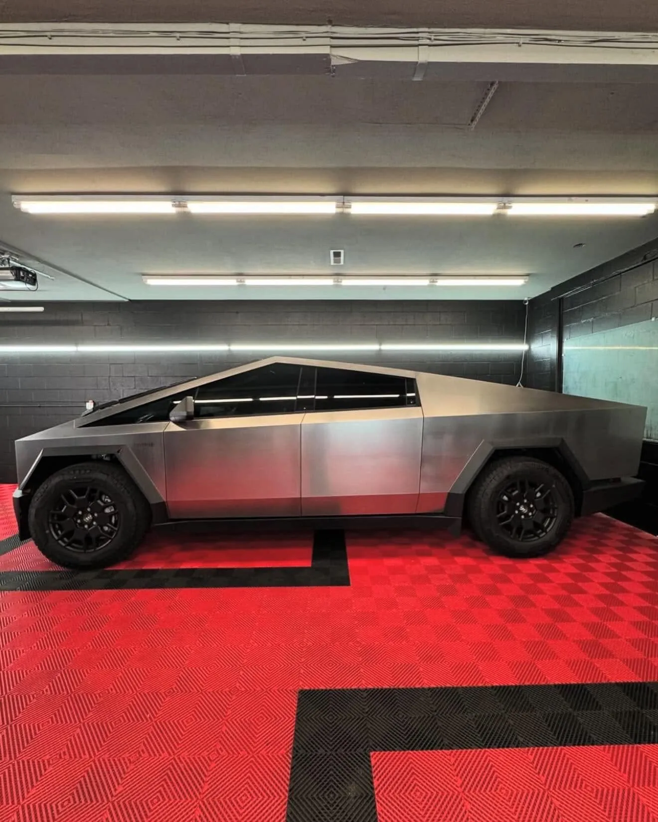 Silver stainless Tesla Cybertruck inside the Redline Tinting install bay on the signature red diamond flooring