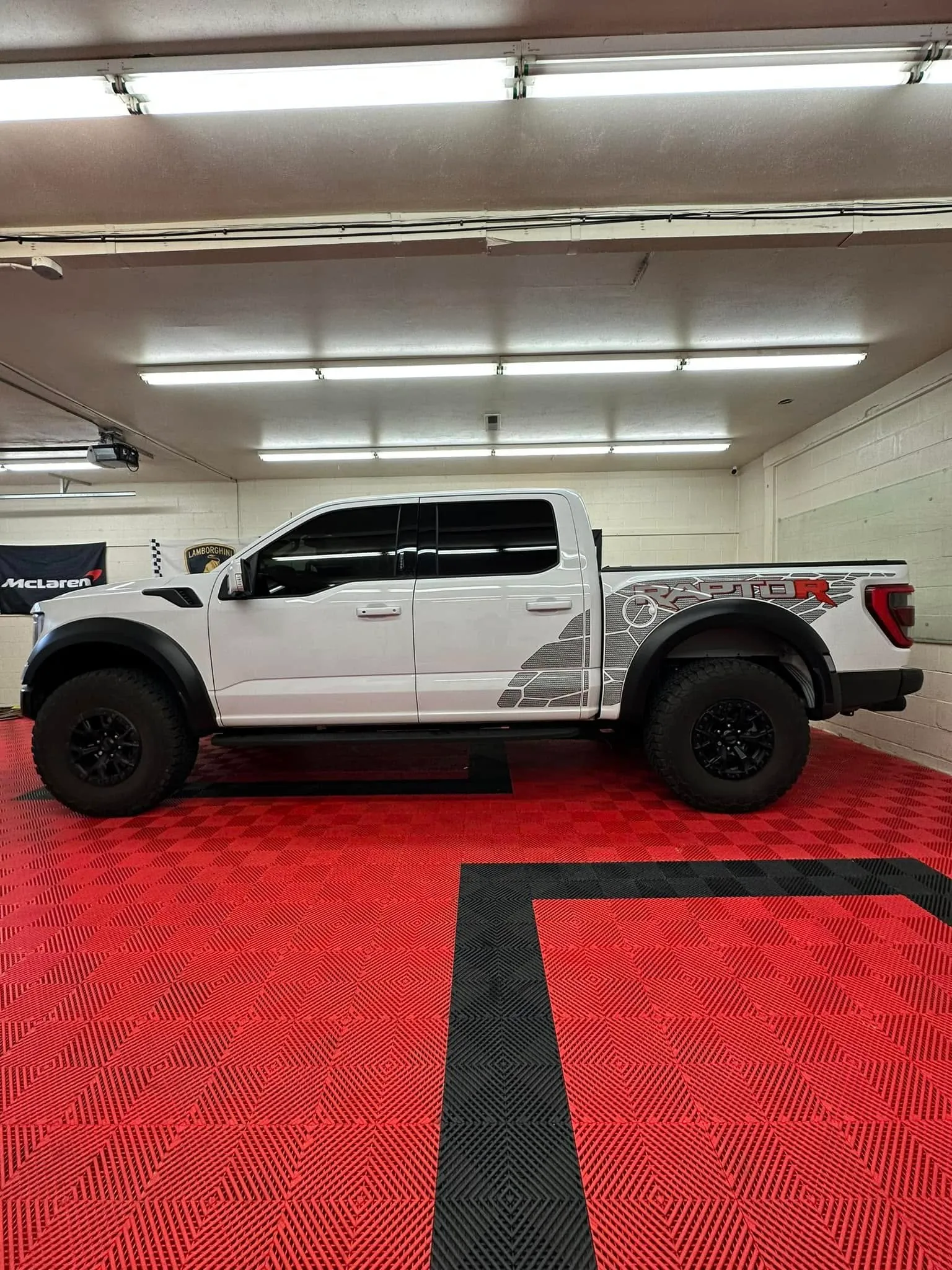 White Ford F-150 Raptor R inside the Redline Tinting bay showing freshly installed XPEL paint protection film and window tint