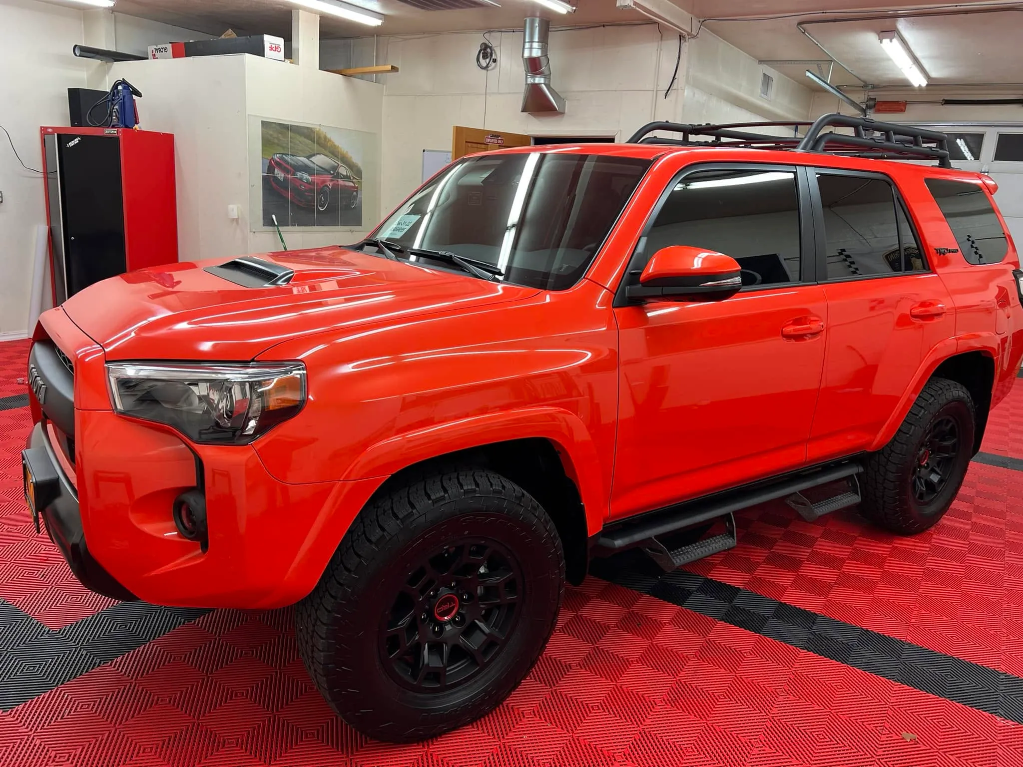Solar Octane orange Toyota 4Runner TRD Pro in the Redline Tinting service bay on the shop's signature red diamond flooring
